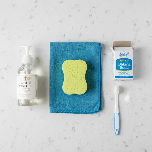 Various essential tools for cleaning a rice cooker lid, including sponges, brushes, and cleaning solutions.