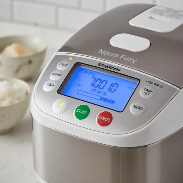 A close-up of the Zojirushi Neuro Fuzzy rice cooker control panel with multi-menu options and LCD timer visible, highlighting its user-friendly features
