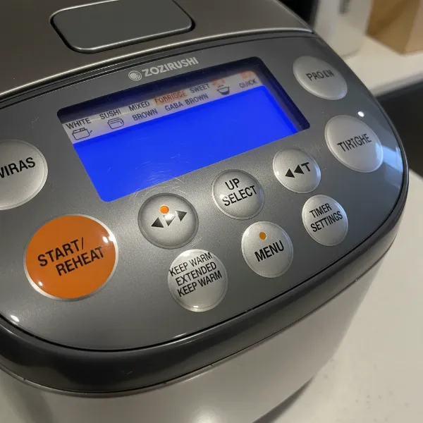 Zojirushi NP-NVC10 rice cooker with its colorful LCD control panel and various cooking settings displayed.